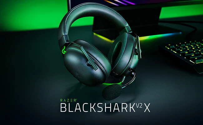 تصویر هدست گیمینگ ریزر مدل  blackshark v2 x در کنار کیبورد و مانیتور