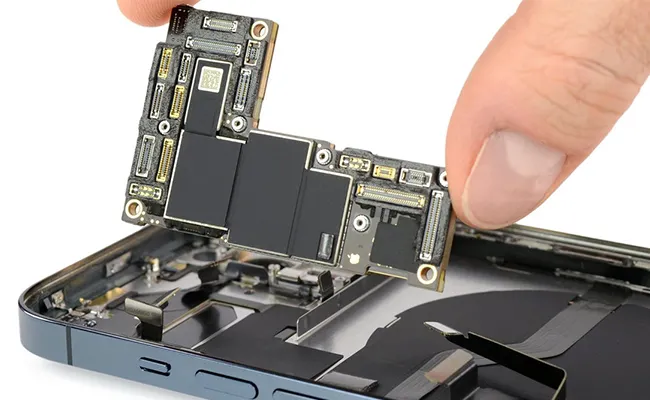 در این عکس یک گوشی تلفن آیفون باز شده که چیپست آن را بیرون آورده‌اند نمایش داده شده است.