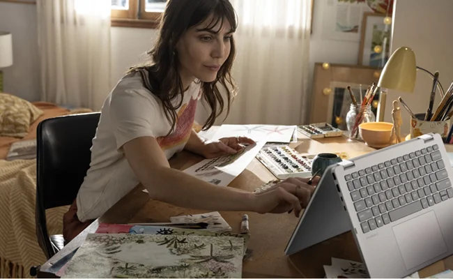 در این عکس یک زن در حال استفاده از لپ تاپ Omnibook 5 Flip 14-fp0023dx HP Ultra 7 نمایش داده شده است.