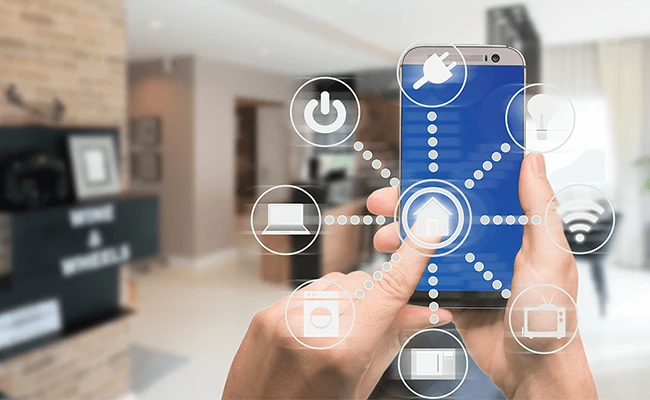 تصویر یک گوشی هوشمند در دست فرد در حال استفاده از گجت خانه هوشمند