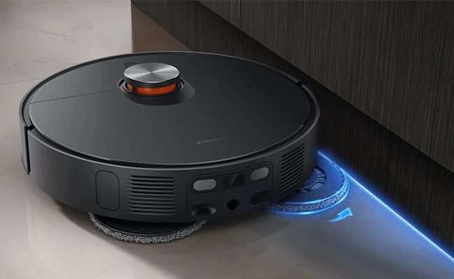 در این عکس یک جارو رباتیک شیائومی Xiaomi X20 MAX در حال تمیز کردن لبه&zwnj;ی دیوار نمایش داده شده است.