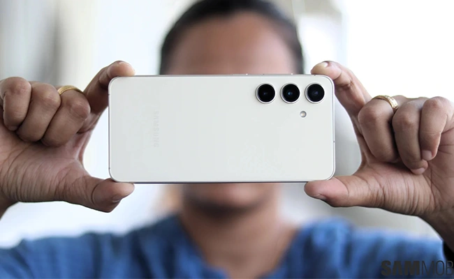 دوربین Samsung Galaxy S26 در این عکس نمای پشتی سامسونگ گلکسی اس ۲۶ در حین عکسبرداری یا فیلمبرداری توسط یک مرد نمایش داده شده است.