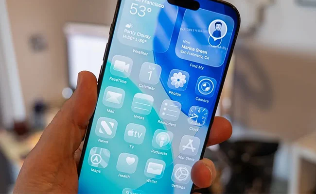 یک گوشی آیفون در دست مردی با نسخه‌ی جدید iOS 26