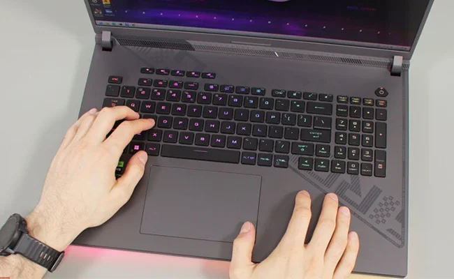 دست مردی که با کیبورد لپ تاپ ROG Strix G18 G814JVR-N6057 ASUS کار می&zwnj;کند.